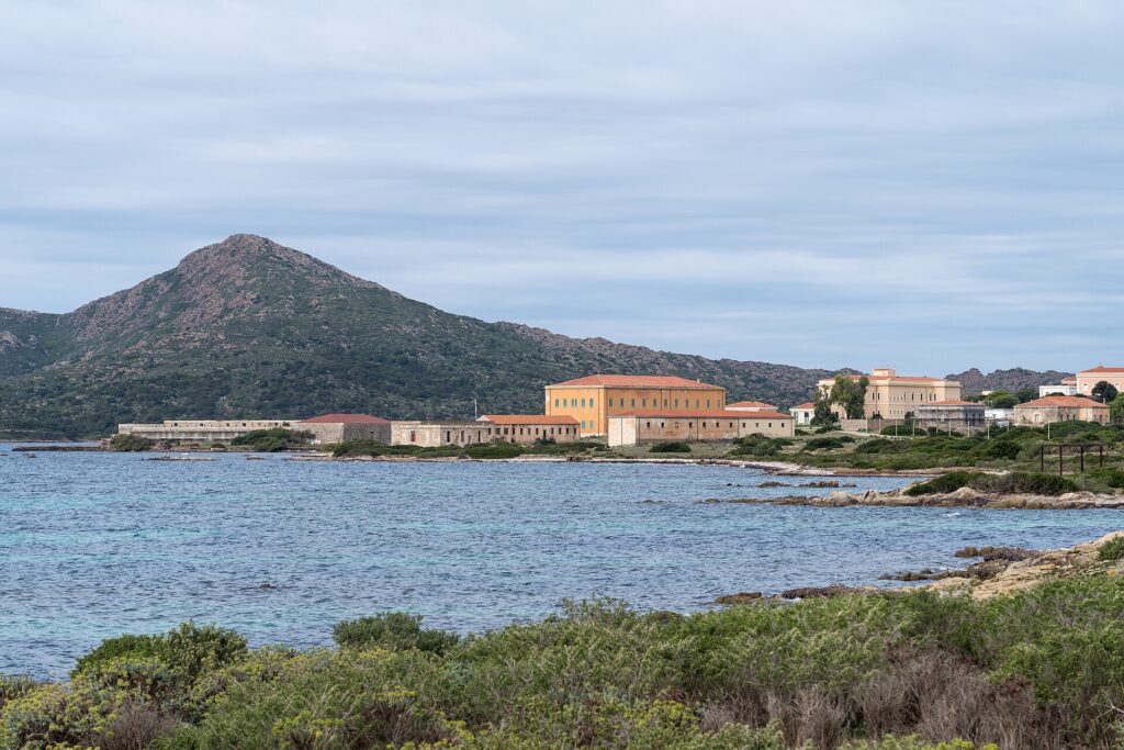 Gli edifici storici di Cala Reale affacciati sul mare, con una collina verde alle spalle